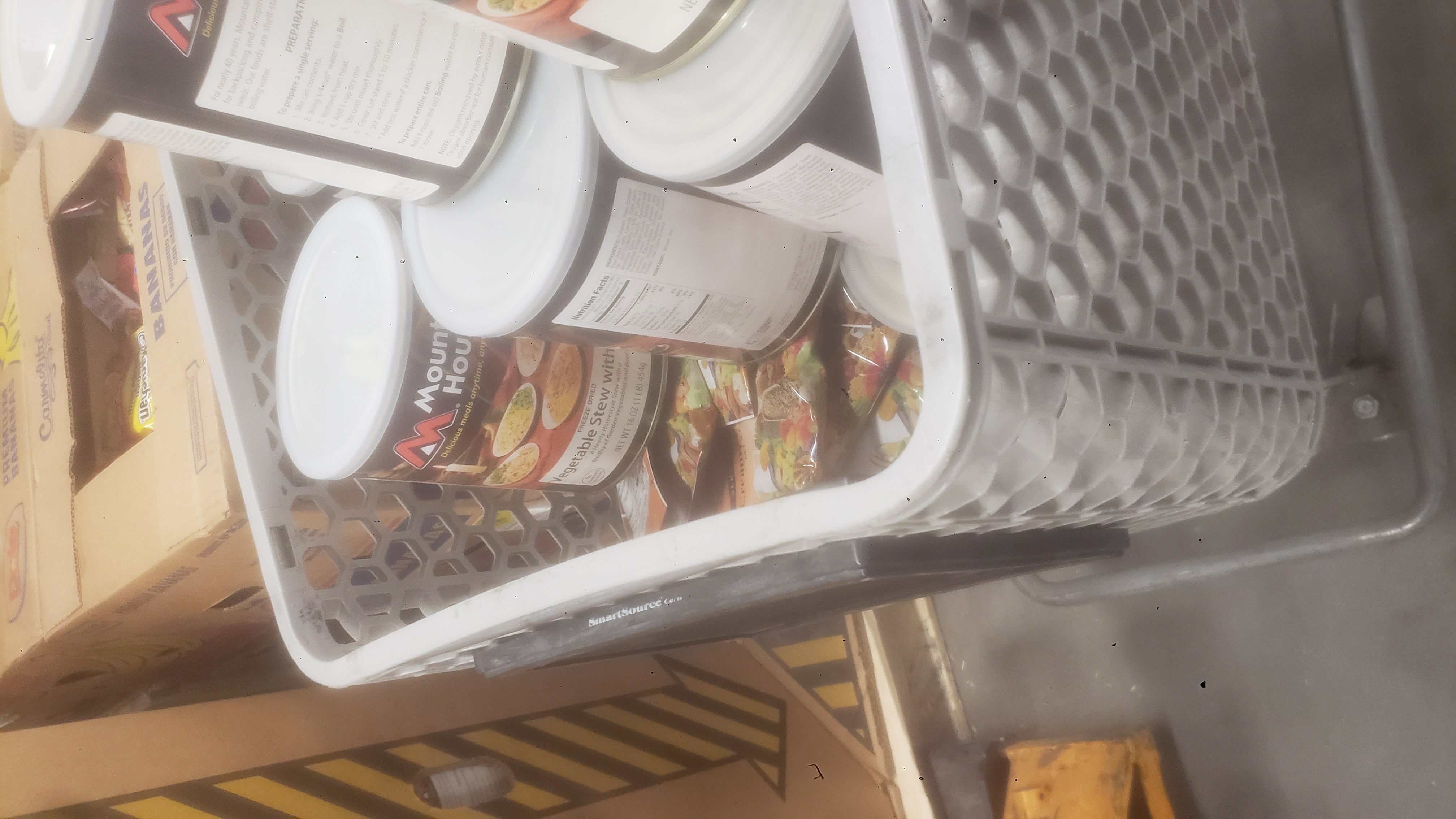Shopping cart filled with cans of freeze dried meals next to a pallet of emergency food boxes